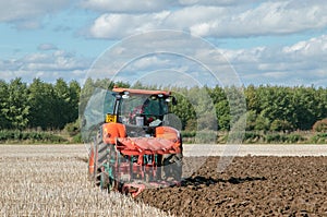 Modern Kubota tractor pulling a plough