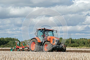 Modern Kubota tractor pulling a plough