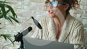 Modern lady speaking at the microphone recording podcast at home using laptop computer. Online new job business freelance for