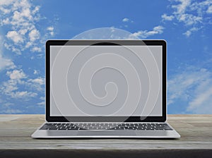 Modern laptop computer with blank screen on wooden table over blue sky with white clouds