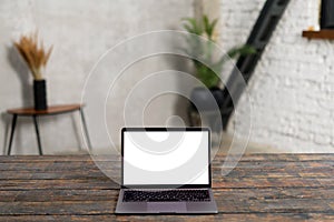 Modern laptop with empty screen on the wooden table with contemporary flat at the background. Mockup, copy space