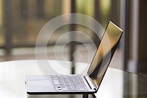 Modern laptop on glass table at sunrise