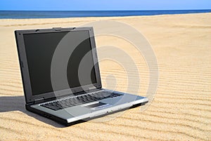 Modern laptop lying on beach