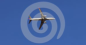 Modern large plane flies overhead against blue sky