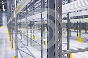 Modern large warehouse space interior, new and modern distribution storage with rows of empty high shelves and racks, concrete and