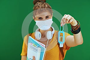 Modern learner woman in shirt against green showing sanitiser