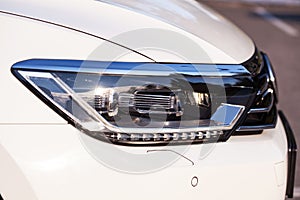 Modern LED headlight on a white car, close up