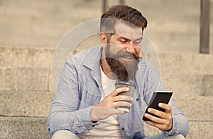 Modern life online communication. Guy with smartphone urban space background. Handsome bearded man relaxing mobile phone