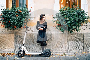 Lifestyle details, happy girl with flowers in urban city enjoying the electric scooter. Happiness and carefree concept