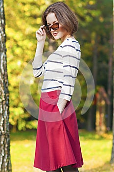 Modern Lifestyle and fashion Concepts: Positive and Smiling Caucasian Brunette Female with Sunglasses Posing in Fall Forest Outdo