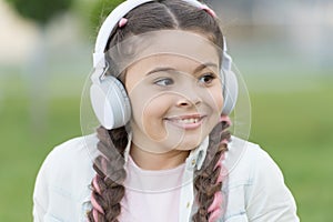 Modern lifestyle. Small child enjoy listening to modern music outdoor. Little girl wearing modern stereo headphones in