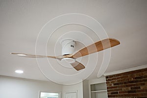 a modern light toned wood fan against a white ceiling in the inside interior of an updated and renovated old house