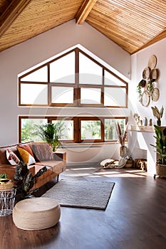 Modern living room with fireplace, sofa, wooden attic ceiling and big window