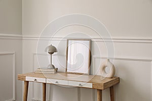 Modern living room, home office. Trendy round vase, beige lamp and old books. Blank picture frame mockup. Bamboo table