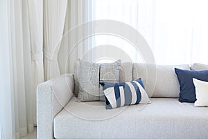 Modern living room interior with comfortable white couch and blue color pillows.