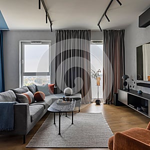 Modern living room interior with gray sofa, black coffee table, orange armchair