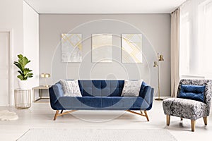 A modern living room interior of a luxurious hotel apartment with a designer couch, an armchair and art decorations. Real photo.