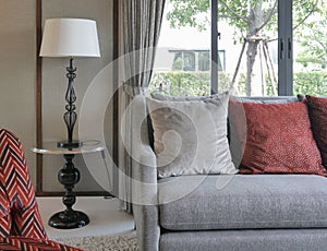 Modern living room with red pillows on sofa and decorative table lamp