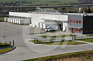 Modern logistics center, white van and trailers standingon ramp