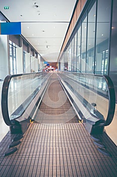 Modern long walkway of escalator moving forward at airport terminal.