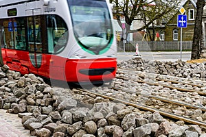 A modern low-floor electric tram runs on newly replaced tracks, unfinished paving works photo