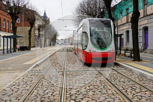 A modern low-floor tram car at a newly built stop platform and paved intermediate track surface