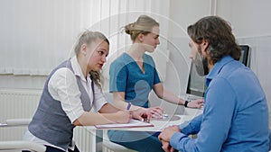 Modern luminous clinic mature patient have a conversation with clinic assistant before to start a health check up at the