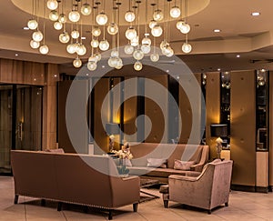 Modern luxurious lobby for hotel with comfortable sofas, arm chairs and moody lighting