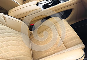 Modern luxury car brown leather interior. Part of orange leather car seat details with white stitching. Interior of prestige car.