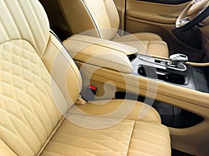 Modern luxury car brown leather interior. Part of orange leather car seat details with white stitching. Interior of prestige car.