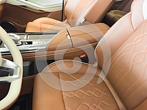 Modern luxury car brown leather interior. Part of orange leather car seat details with white stitching. Interior of prestige car.