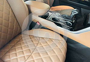 Modern luxury car brown leather interior. Part of orange leather car seat details with white stitching. Interior of prestige car.