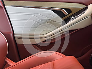 Modern luxury car brown leather interior. Part of orange leather car seat details with white stitching. Interior of prestige car.