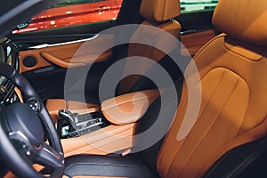 Modern Luxury car inside. Interior of prestige modern car. Comfortable leather brown seats. Orange perforated leather