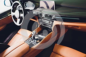 Modern Luxury car inside. Interior of prestige modern car. Comfortable leather brown seats. Orange perforated leather