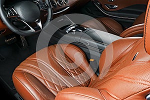 Modern Luxury car inside. Interior of prestige modern car. Comfortable leather seats.Orange perforated leather cockpit. Steering