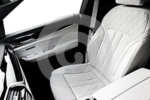 Modern luxury car white leather interior with natural wood panel. Part of leather car seat details with stitching. Interior with d