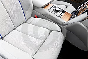 Modern luxury car white leather interior with natural wood panel. Part of leather car seat details with stitching. Interior of pre