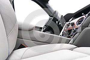 Modern luxury car white leather interior with natural wood panel. Part of leather car seat details with stitching. Interior of pre