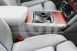 Modern luxury car white leather interior with natural wood panel. Part of leather car seat details with stitching. Interior of pre