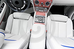 Modern luxury car white leather interior with natural wood panel. Part of leather car seat details with stitching. Interior of pre