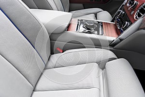 Modern luxury car white leather interior with natural wood panel. Part of leather car seat details with stitching. Interior of pre