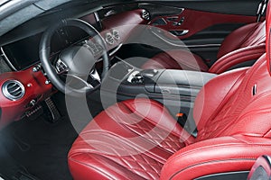 Modern luxury prestige car interior, dashboard, steering wheel. Comfortable perforated leather seats. Red perforated leather