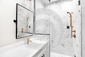 A modern, luxury white bathroom with gold hardware.