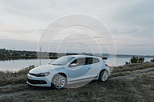 Modern luxury white sedan 2-doors sport car at the sunset outdoors.