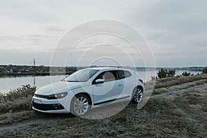 Modern luxury white sedan 2-doors  sport car at the sunset outdoors.