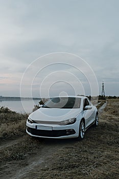 Modern luxury white sedan 2-doors sport car at the sunset outdoors.