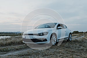 Modern luxury white sedan 2-doors  sport car at the sunset outdoors