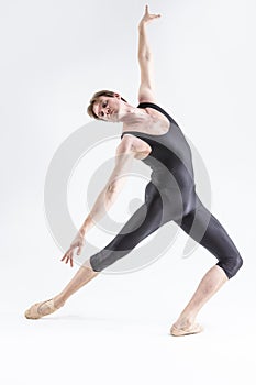 Modern Ballet Dancer Young Caucasian Athletic Man in Black Suit Posing Stretching in Studio On White With Lifted Hands