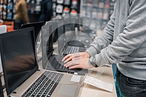 Modern male customer choosing laptop in the computer store